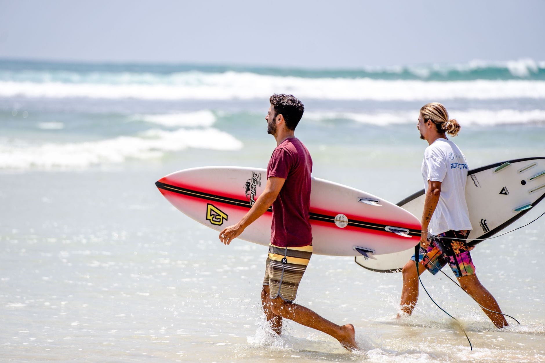 Two surfers carrying boards on a sunny beach in Sri Lanka